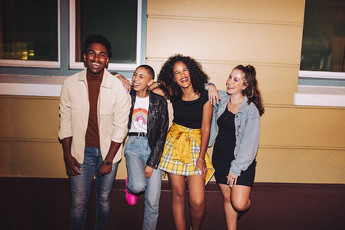 Cheerful friends leaning against a wall at night