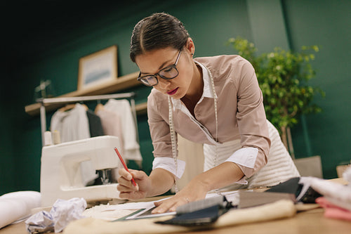 Female tailor designing clothes pattern on paper