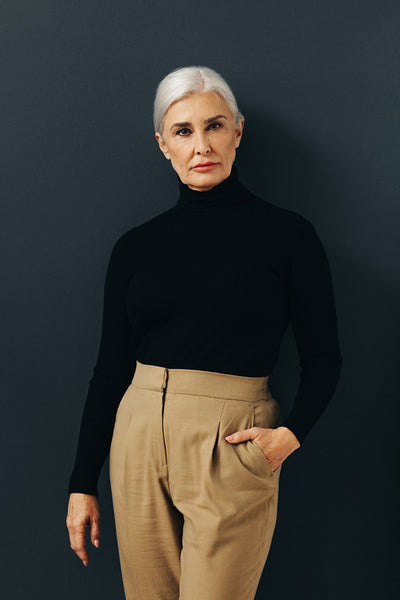 Empowered and elegant: Senior woman with grey hair standing in a studio dressed in businesswear