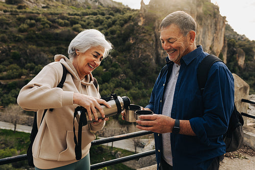 Happy senior couple taking a coffee break while hiking in the hi