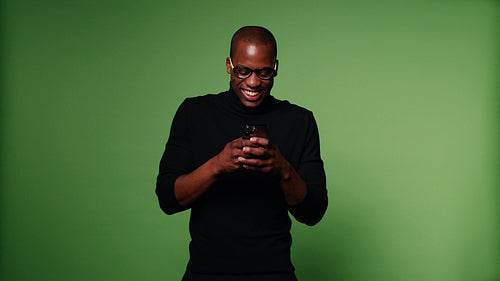 Happy black man using his smartphone on green background