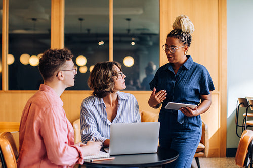 Three coworkers discussing tasks together in a modern office environment