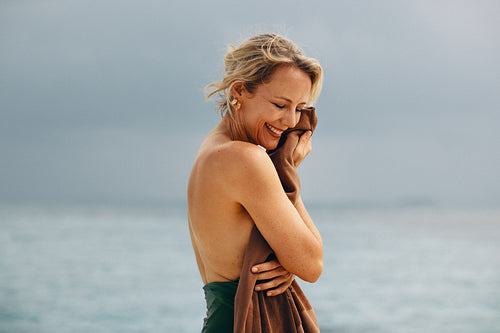 Smiling woman enjoying serenity of the beach with sea and cloudy sky