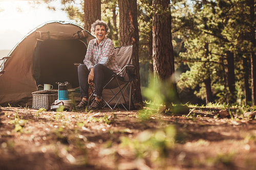 Senior woman sitting relaxed outside a tent