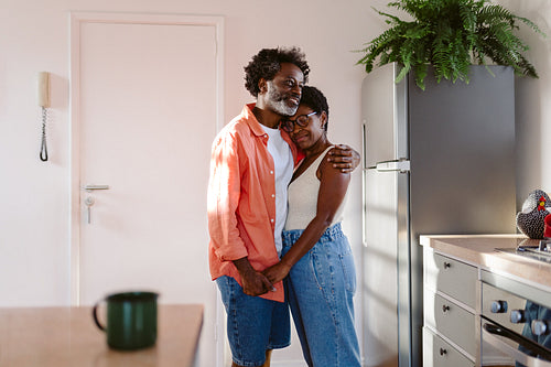 Black Brazilian couple enjoying each other's company, holding hands and hugging at home