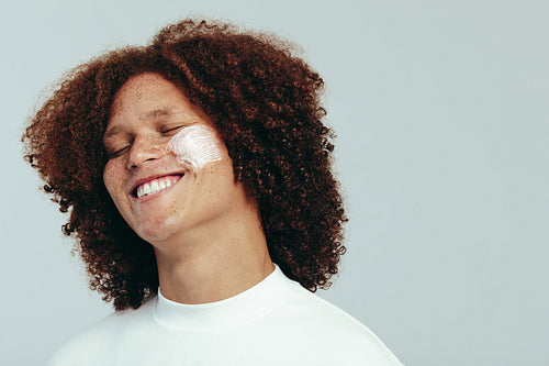 Young man taking on a skincare routine with beauty cream for his face