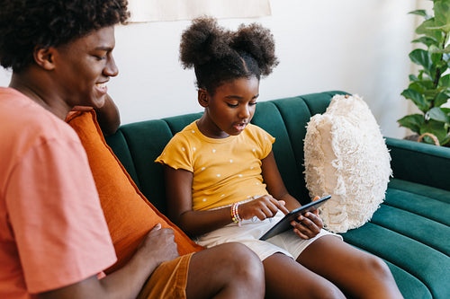 Two siblings enjoying digital connection with a tablet in the living room