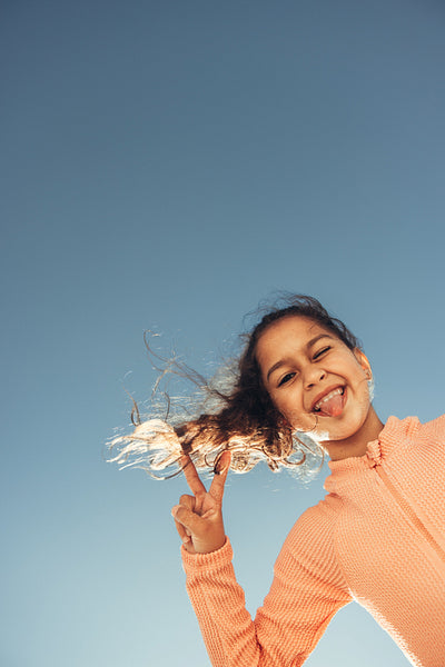 Cute little girl showing the peace sign with her tongue out