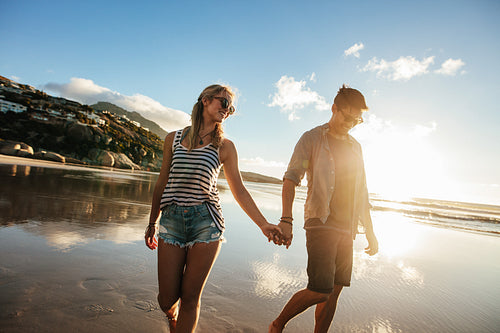 Loving couple walking on sea shore holding hands