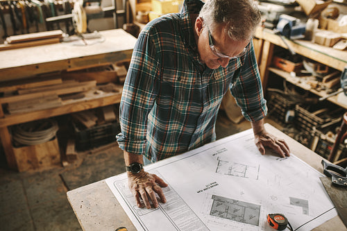 Senior carpenter studying blueprint at workshop