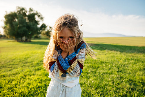 Young girl giggling playfully in sunny meadow outdoors