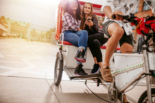 Young women sitting on tricycle and posing for selfie