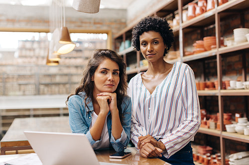 Confident female ceramists looking at the camera in their shop