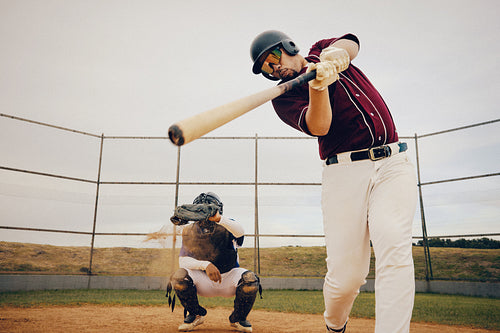 Baseball player in helmet taking powerful swing with catcher ready on the field during an intense game