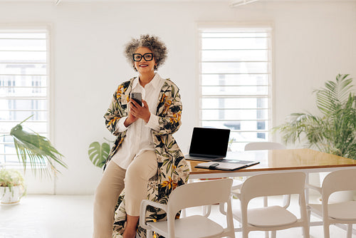 Happy senior businesswoman using a smartphone in a boardroom