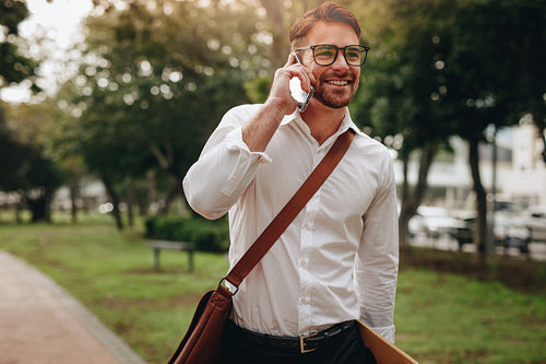 Businessman talking on mobile phone walking in street