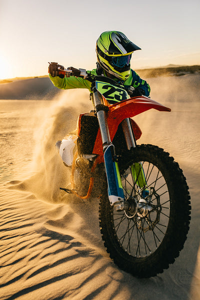 Motocross biker racing in sand dunes during a race