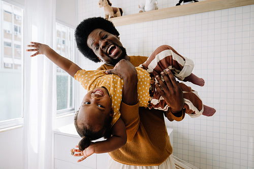 Joyful dad lifts smiling child in bright room