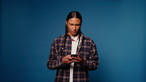 Young man with braids smiles at his phone