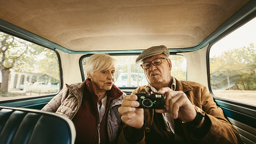 Old couple in car looking at the pictures on camera