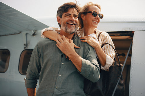 Smiling mature couple enjoying a luxury holiday adventure near a private plane