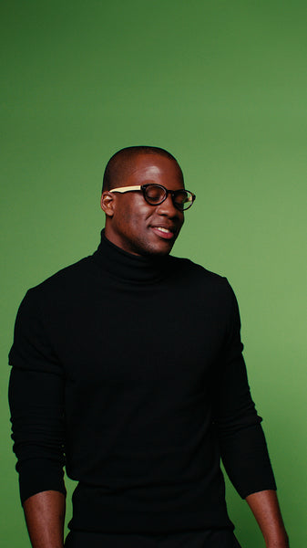 Confident man in black turtleneck and glasses against a green screen