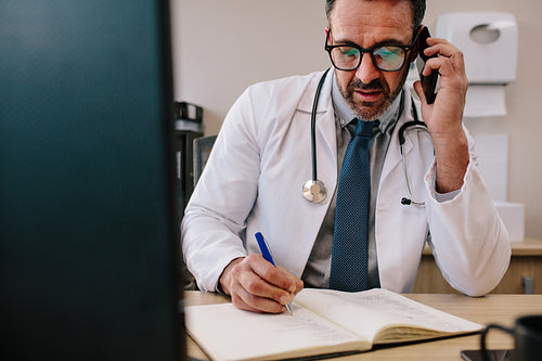 Doctor talking on cell phone and making notes