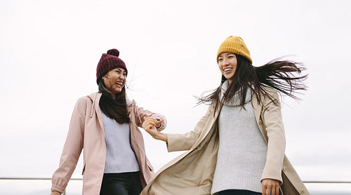 Cheerful girl friends in winter clothes standing together outdoors