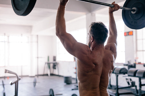 Bodybuilder exercising with weights at gym