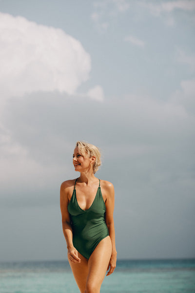 Woman in green swimsuit smiling on a sunny tropical beach