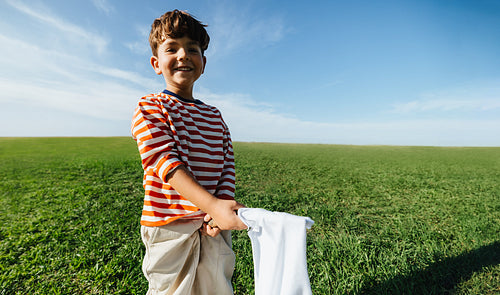 Child uses white cloth as pretend prop outdoors