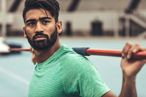 Close up of an athlete standing in a track and field stadium holding a javelin