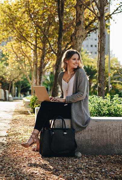 Smiling woman sitting outdoors with laptop