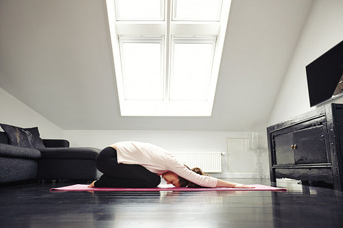 Young caucasian woman exercising yoga in living room