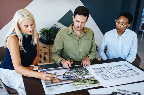 Group of diverse professionals discussing architectural blueprints in a modern office setting