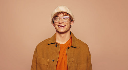 Stylish man in denim jacket and glasses on peach background