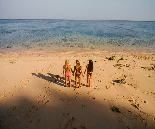 Female friends standing on the beach holding hands
