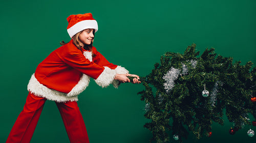 Santa girl setting up a christmas tree