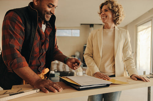 Happy contractor and homeowner signing the paperwork for their home renovation agreement