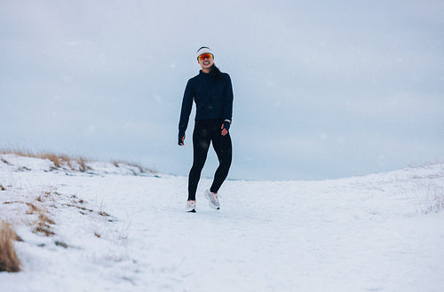 Standing woman on a snowy path wears sportswear outdoors in winter