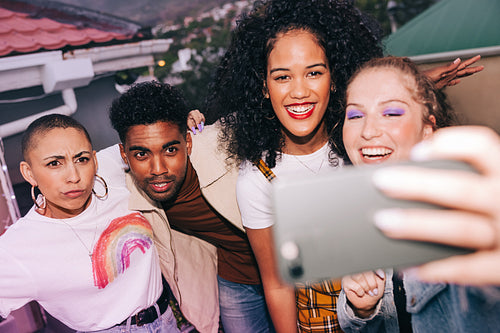 Group of friends posing for a selfie on a rooftop