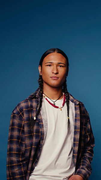 Young man with braids laughs on blue background