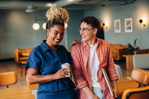 Friendly colleagues smiling and talking while having a break in an office setting