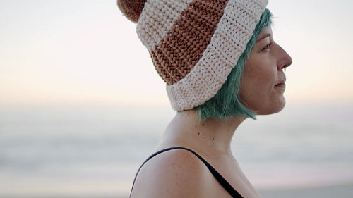 Woman with knitted hat smiling on the beach