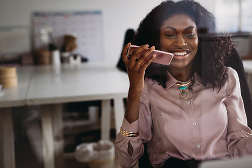 Businesswoman talking over mobile phone on loudspeaker while working at home