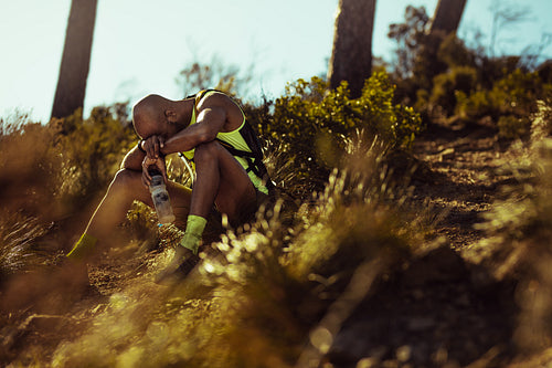 Runner looking tired taking rest on mountain trail