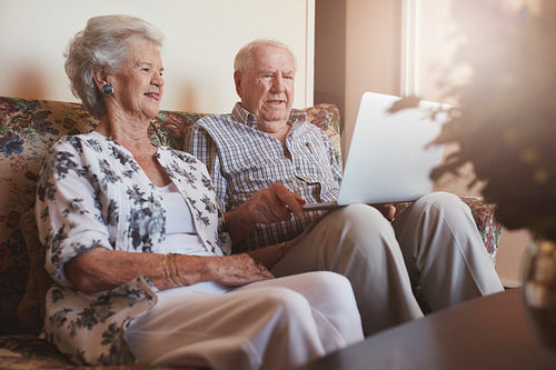 Senior couple sitting together and using laptop