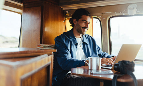 Relaxed traveler works on a laptop inside a cozy van