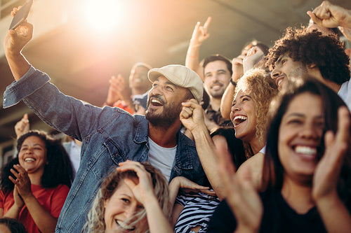 Group of supporters taking selfie watching a football match