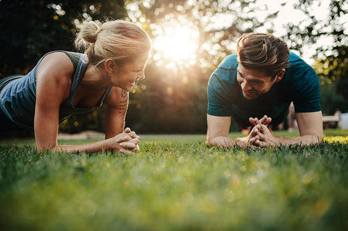 Fit young man and woman exercising in park